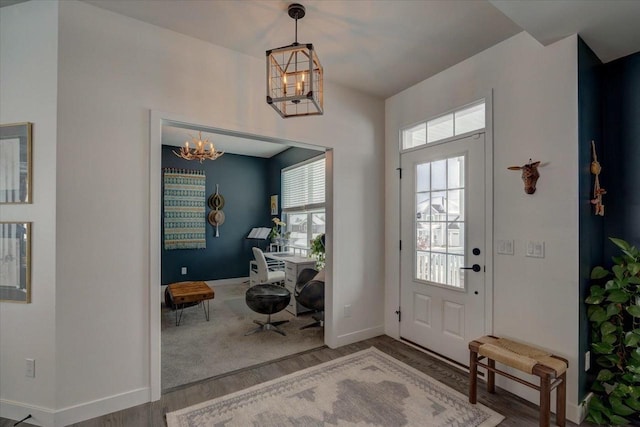 entryway with baseboards, a chandelier, and wood finished floors