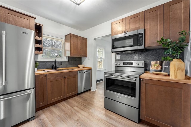 kitchen featuring sink, backsplash, wooden counters, light hardwood / wood-style floors, and stainless steel appliances