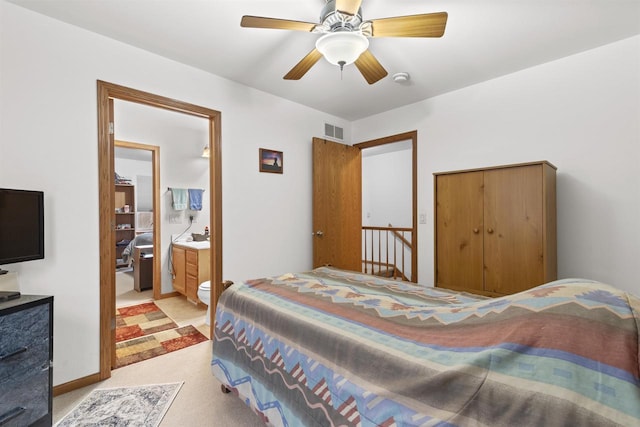 bedroom with light colored carpet, ceiling fan, and ensuite bathroom