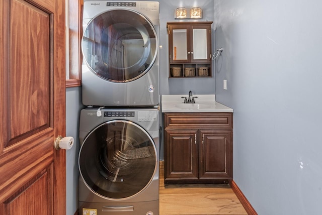 washroom with cabinets, sink, light wood-type flooring, and stacked washing maching and dryer