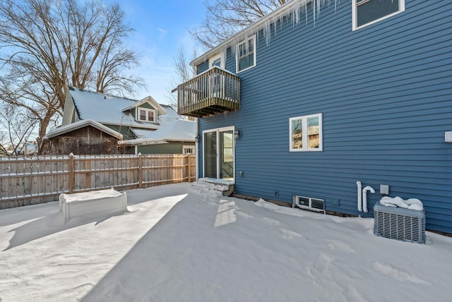 snow covered rear of property with a balcony