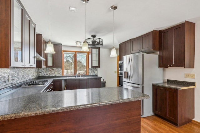 8209 N Port Washington Rd, Fox Point, WI 53217 - kitchen featuring stainless steel appliances, a sink, dark countertops, glass insert cabinets, and pendant lighting