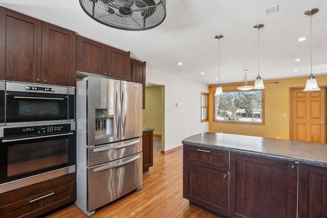 8209 N Port Washington Rd, Fox Point, WI 53217 - kitchen featuring stainless steel appliances, dark countertops, decorative light fixtures, and light wood-style flooring