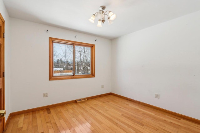 8209 N Port Washington Rd, Fox Point, WI 53217 - spare room with baseboards, a notable chandelier, visible vents, and light wood-style floors