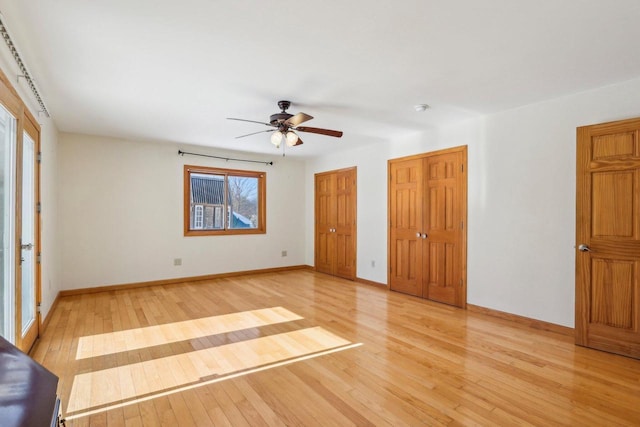 8209 N Port Washington Rd, Fox Point, WI 53217 - unfurnished bedroom with light wood-style floors, baseboards, multiple closets, and a ceiling fan