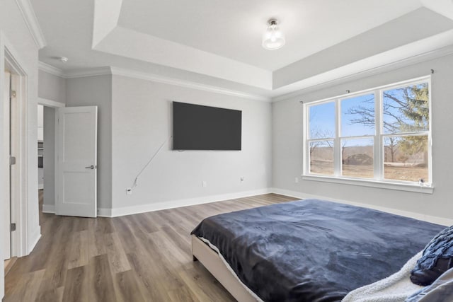 bedroom featuring crown molding, wood-type flooring, and a raised ceiling