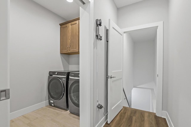 laundry area with cabinets, washing machine and clothes dryer, and light hardwood / wood-style flooring