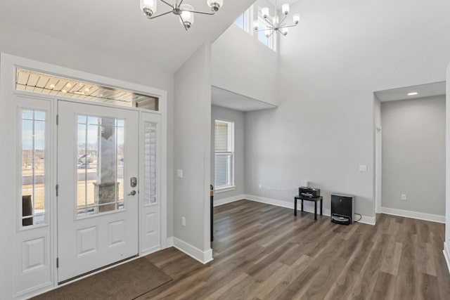 foyer featuring dark hardwood / wood-style flooring, a notable chandelier, and a towering ceiling