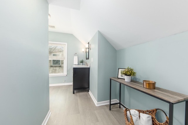 corridor with lofted ceiling and sink