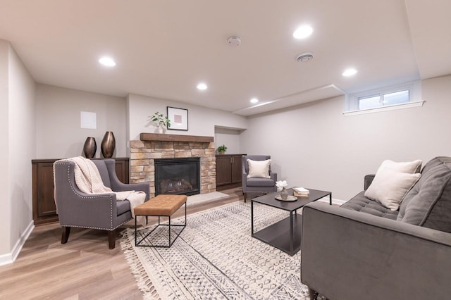 living room with a stone fireplace and light hardwood / wood-style floors