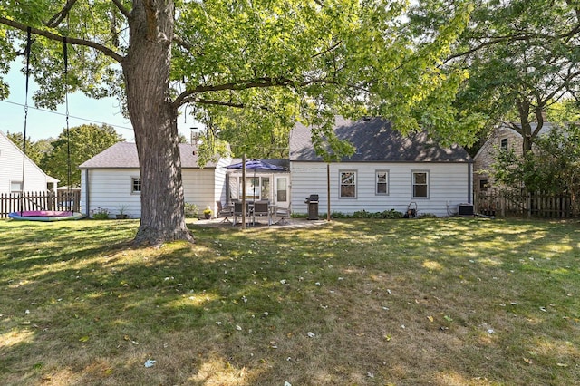 rear view of house featuring cooling unit, a patio area, and a lawn