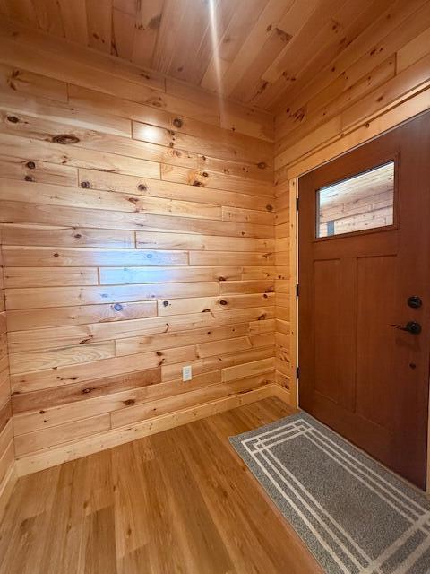 foyer entrance featuring hardwood / wood-style floors, wood ceiling, and wood walls