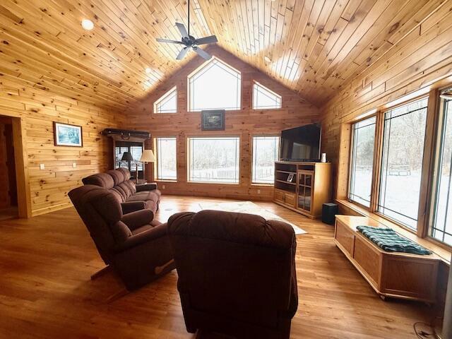 living room featuring wood ceiling, wooden walls, and a wealth of natural light