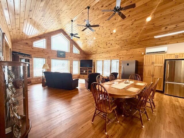 dining area featuring wood ceiling, hardwood / wood-style floors, high vaulted ceiling, a wall mounted AC, and wood walls