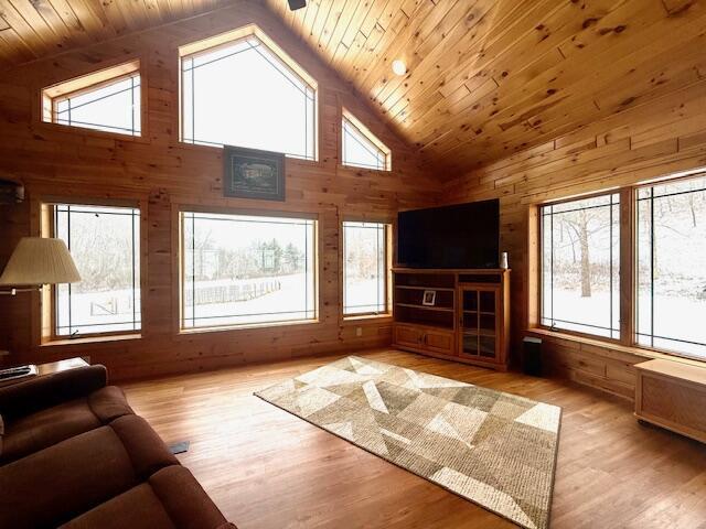 living room featuring high vaulted ceiling, light hardwood / wood-style flooring, wood ceiling, and wood walls