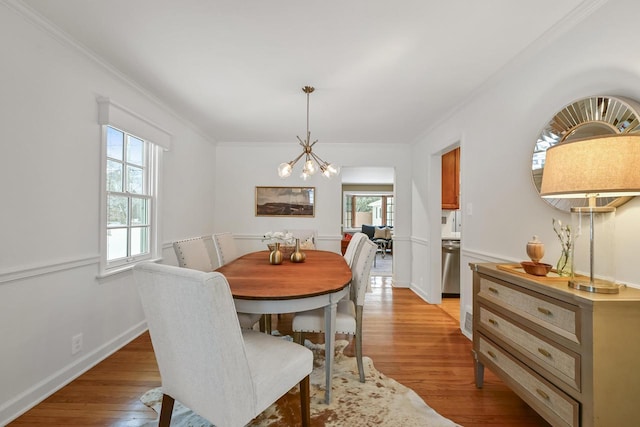 dining space featuring ornamental molding, a chandelier, and light wood-type flooring