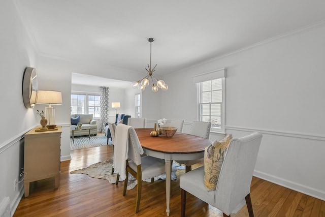 dining room with an inviting chandelier, dark wood-type flooring, and ornamental molding