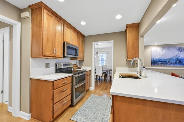 kitchen with sink, stainless steel appliances, kitchen peninsula, and light wood-type flooring