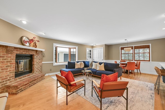 living room featuring a brick fireplace and light hardwood / wood-style flooring