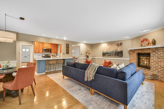 living room with sink, a brick fireplace, and light wood-type flooring