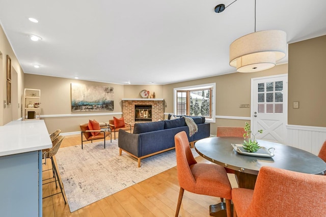 dining space featuring a brick fireplace and light hardwood / wood-style floors