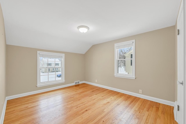 additional living space featuring vaulted ceiling, a wealth of natural light, and light wood-type flooring