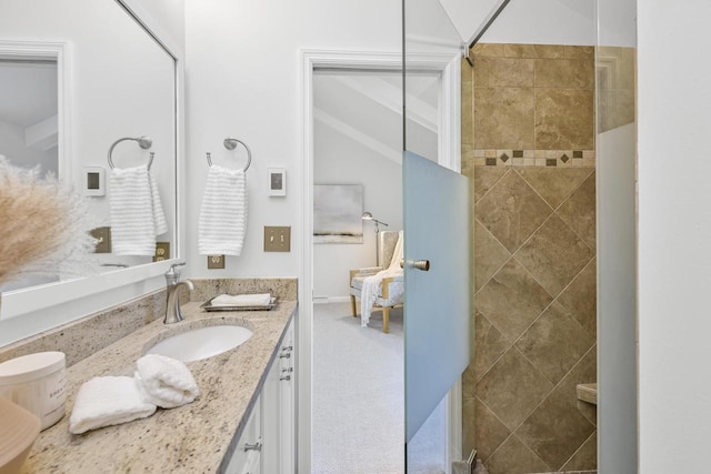 bathroom with tiled shower and vanity