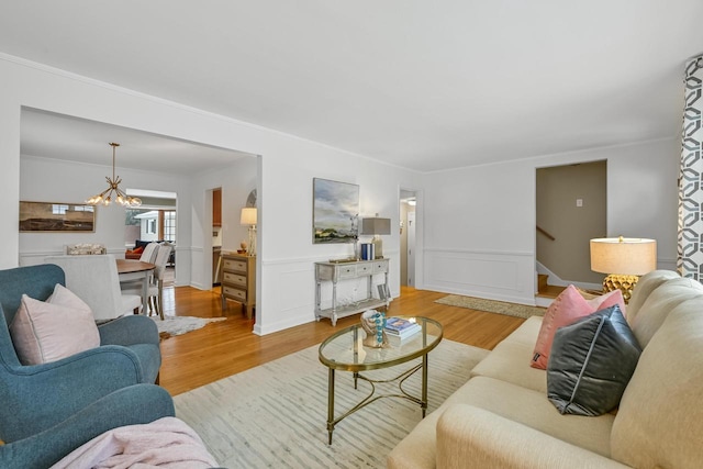 living room featuring an inviting chandelier, ornamental molding, and light wood-type flooring