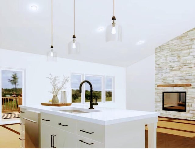 kitchen featuring lofted ceiling, a stone fireplace, sink, pendant lighting, and white cabinets