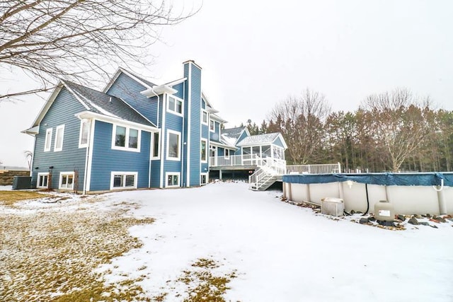 snow covered rear of property with a pool side deck