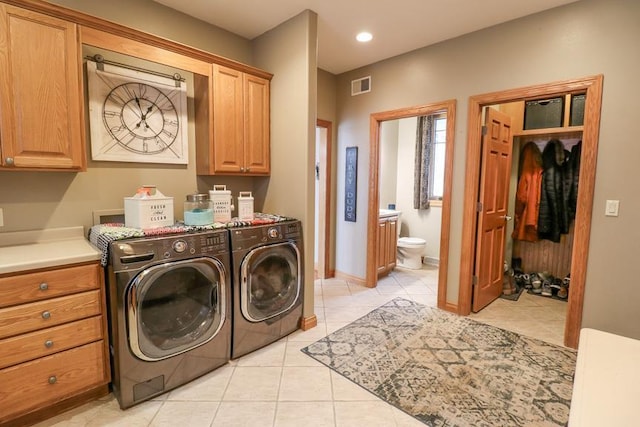 washroom with cabinets, washer and clothes dryer, and light tile patterned floors