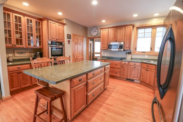 kitchen featuring a kitchen island, light hardwood / wood-style floors, appliances with stainless steel finishes, and a kitchen bar