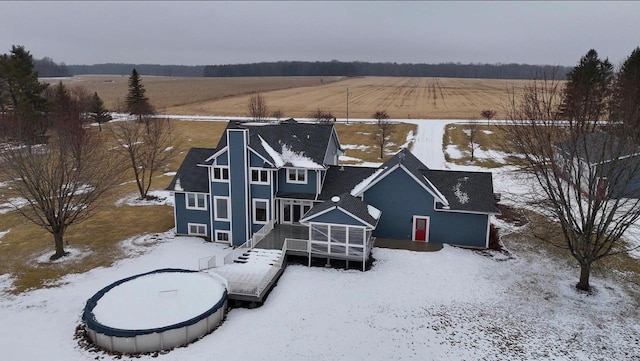 snow covered house featuring a rural view