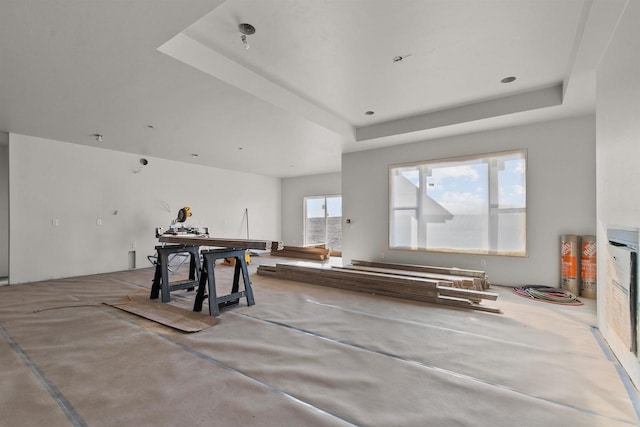 miscellaneous room with a tray ceiling and concrete flooring