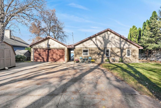 rear view of house with a garage, a yard, and a shed