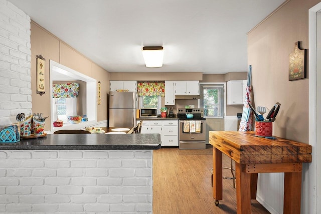 kitchen featuring appliances with stainless steel finishes, light hardwood / wood-style flooring, white cabinets, and kitchen peninsula