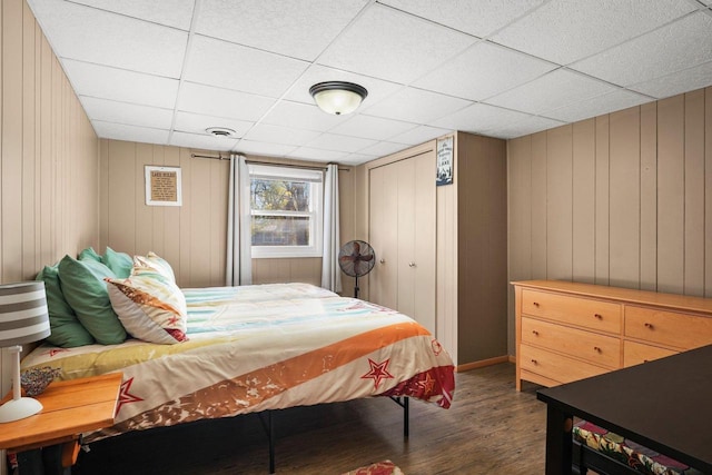 bedroom with dark wood-type flooring, a drop ceiling, and a closet