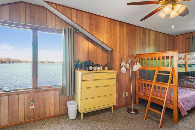 carpeted bedroom featuring a water view, lofted ceiling, and wooden walls