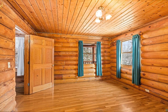 unfurnished room featuring a healthy amount of sunlight, rustic walls, light hardwood / wood-style floors, and wooden ceiling