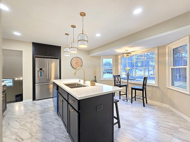 kitchen with decorative light fixtures, sink, a kitchen breakfast bar, a kitchen island with sink, and stainless steel appliances