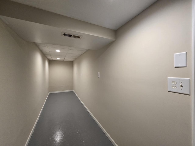 hallway with a paneled ceiling and concrete floors