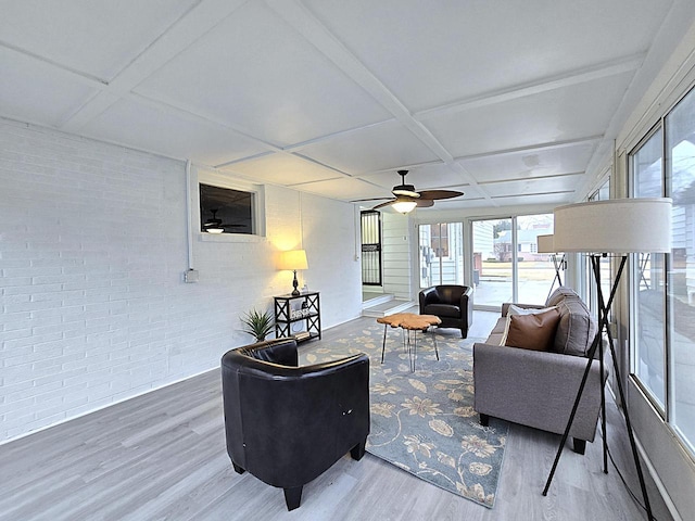 living room with ceiling fan, brick wall, wood-type flooring, and coffered ceiling