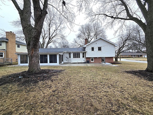 back of house with a sunroom, a patio area, and a lawn