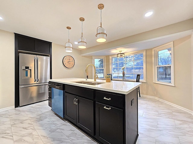 kitchen with pendant lighting, stainless steel appliances, sink, and a center island with sink