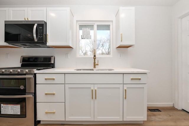 kitchen featuring white cabinetry, sink, light wood-type flooring, and range with two ovens