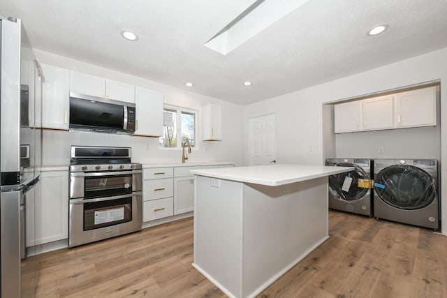 kitchen with a center island, stainless steel appliances, separate washer and dryer, and white cabinets