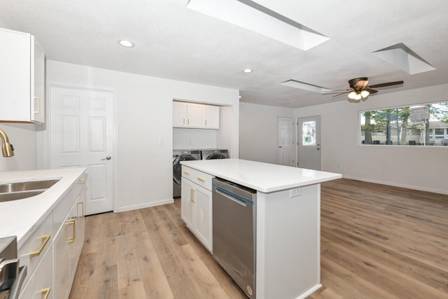 kitchen with sink, dishwasher, washing machine and dryer, a center island, and white cabinets