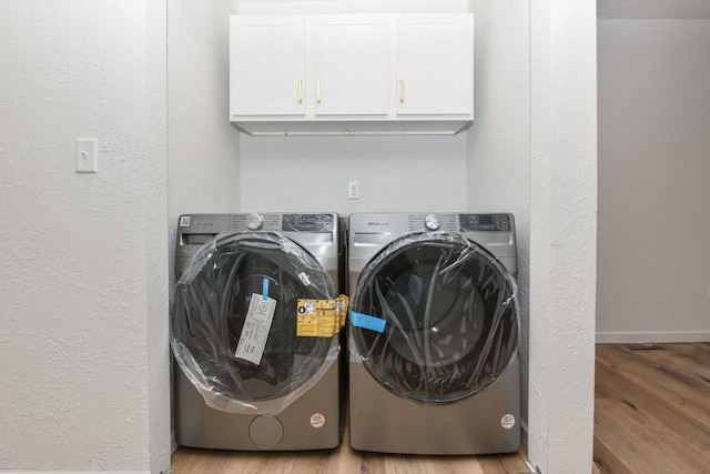 washroom with separate washer and dryer, light hardwood / wood-style flooring, and cabinets