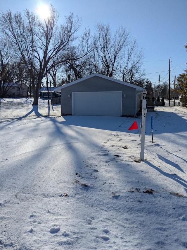 view of snow covered exterior with a garage and an outbuilding