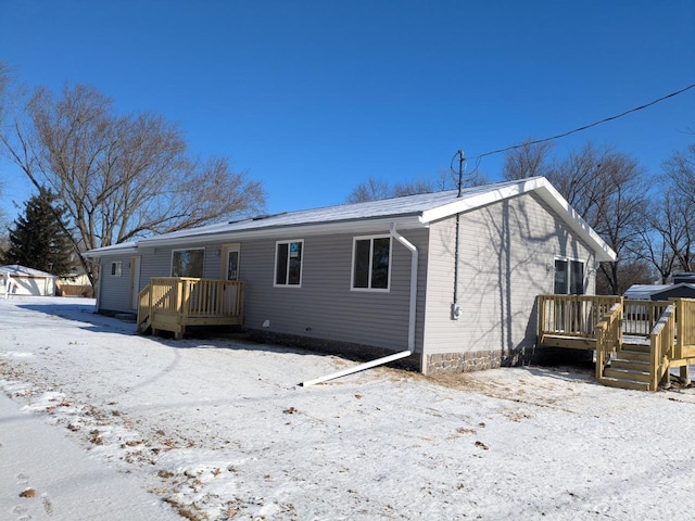 snow covered house with a wooden deck